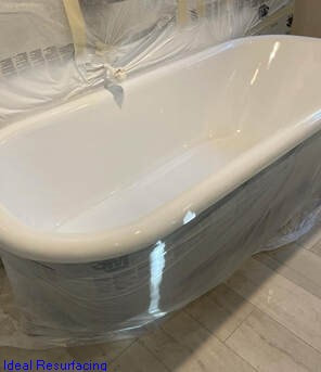 Image of a bathtub that is getting refinished by Ideal Resurfacing. You can see the bathtub has a fresh white coat.